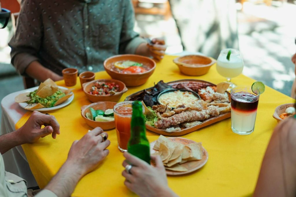 Este artículo habla sobre platos latinos populares en Estados Unidos. La foto muestra una mesa con comida latina donde hay varios comensales.