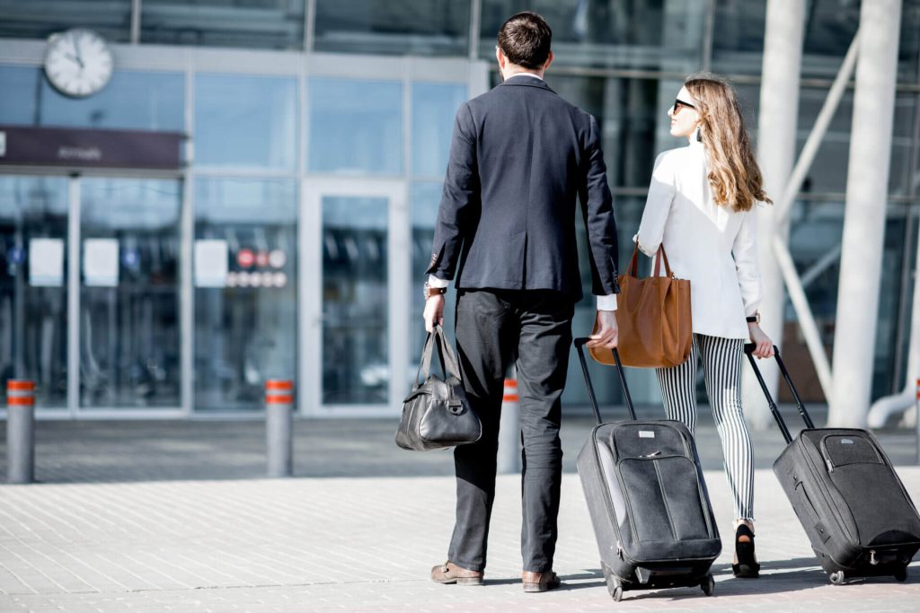 Pareja con maletas de espalda ingresando al aeropuerto para hacer una escala gracias a la visa de transito USA