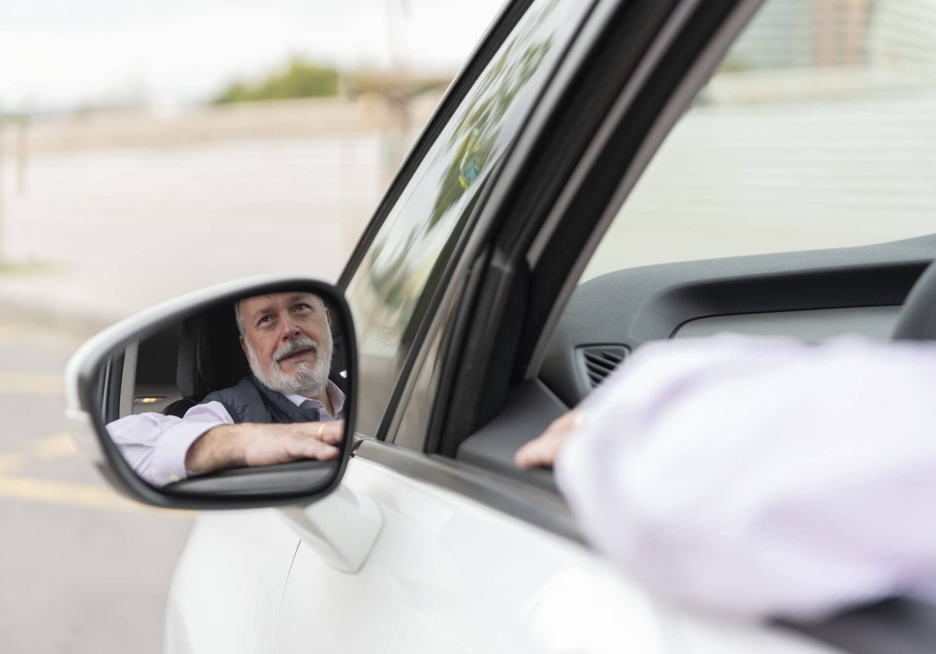 Hombre mayor mirando por el retrovisor de su auto tras obtener una licencia de conducir para indocumentados en pensilvania