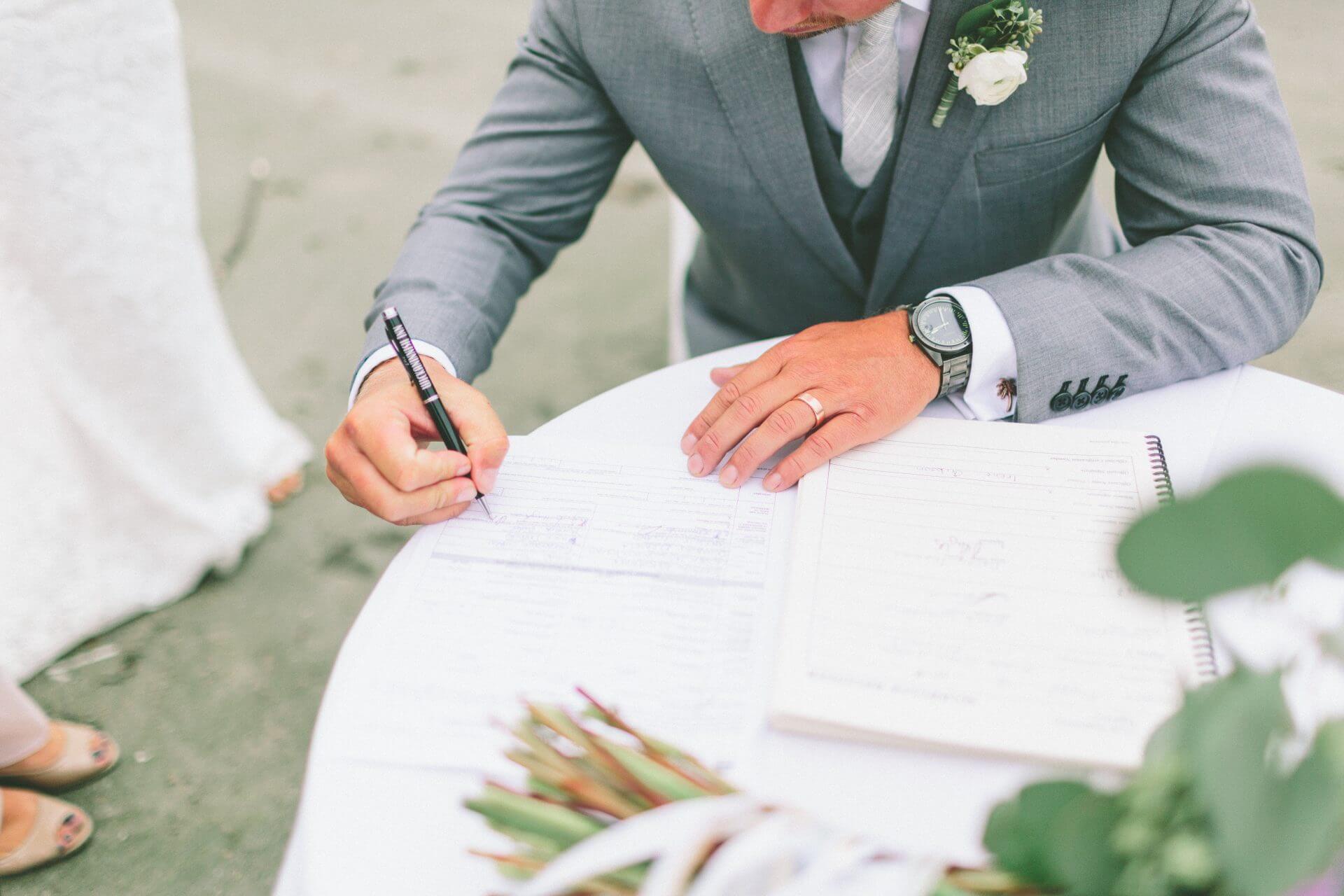 Marido firmando documentos de matrimonio tras averiguar que necesito para casarme en usa