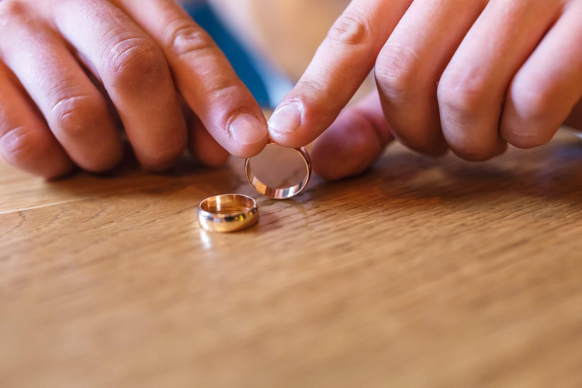 Manos del novio con anillos de compromiso en la mesa tras investigar si dos inmigrantes se pueden casar en estados unidos
