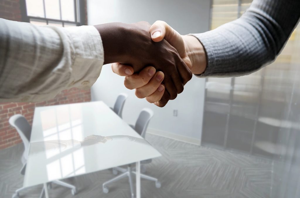 Dos personas estrechándose formalmente la mano luego de la entrevista para la ciudadania americana
