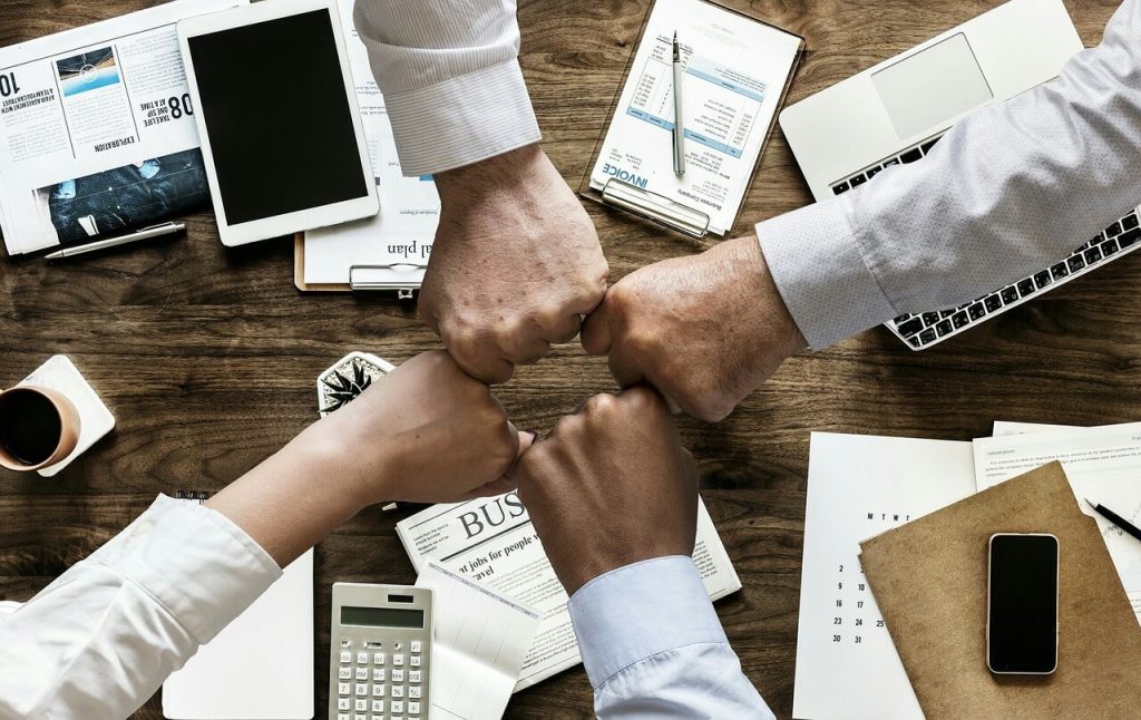 Grupo de personas con permisos de trabajo juntando las manos celebrando el trabajo